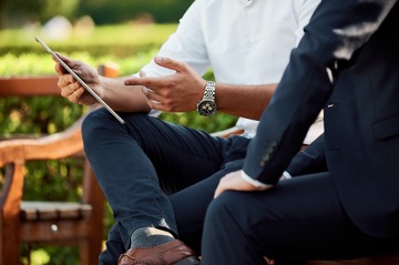 Stock image of professionals sitting on a bench amongst greenery