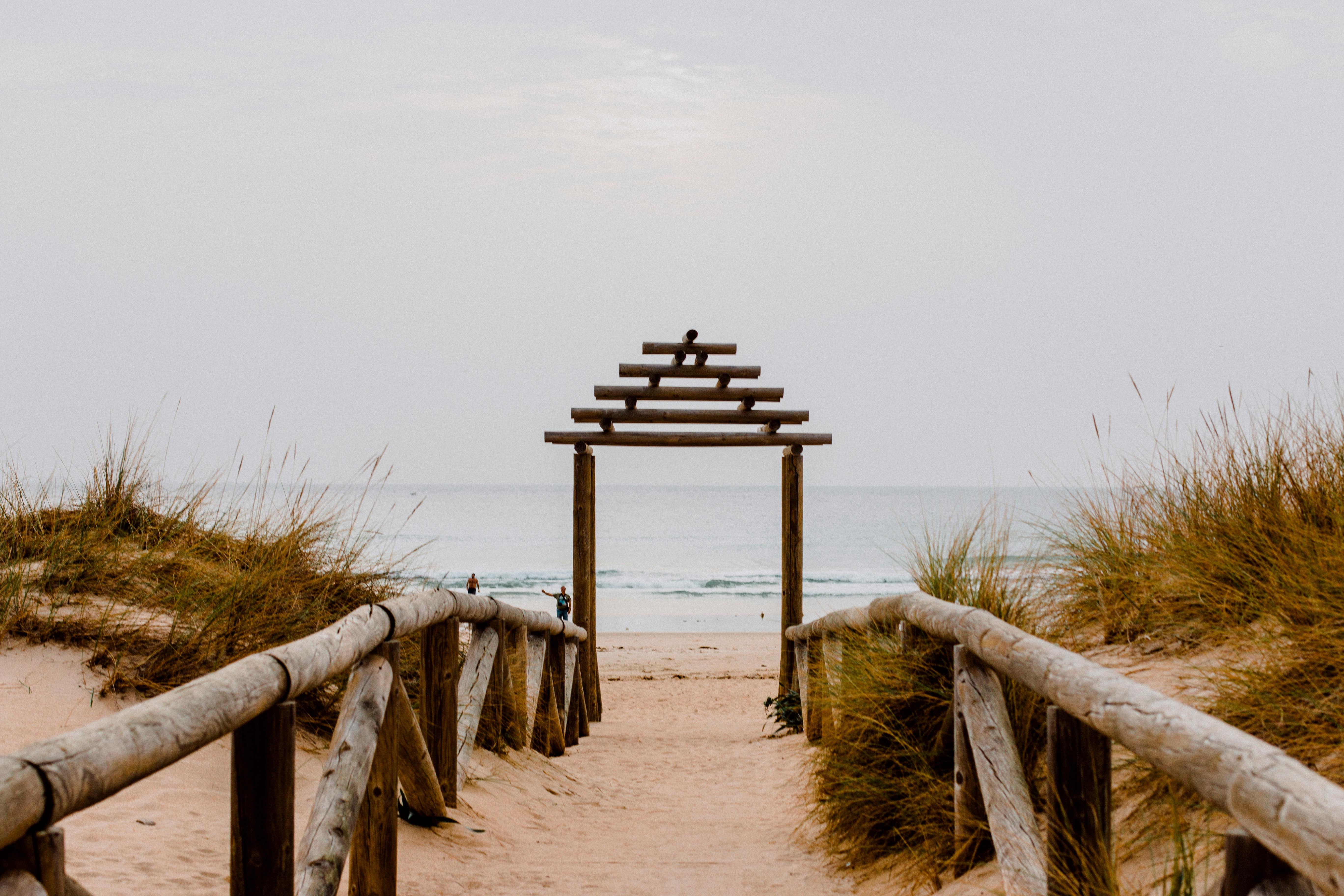 Ornate wooden archway entrance to public beach with sand-based flora on each side